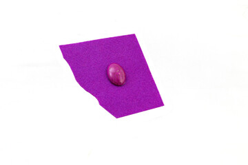 Piece of purple felt with oval bead for embroidery isolated on white background. Handcraft, process...