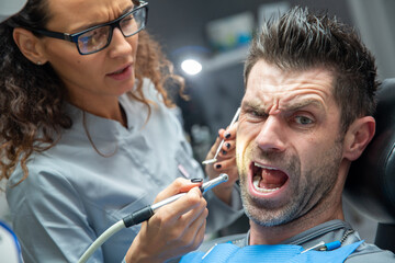 Attractive young woman in stomatology clinic with male dentist. Healthy teeth concept.
