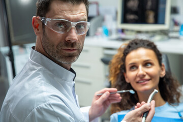 Attractive young woman in stomatology clinic with male dentist. Healthy teeth concept.
