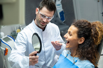 Attractive young woman in stomatology clinic with male dentist. Healthy teeth concept.
