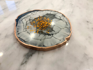 Cup holder, epoxy resin tray, marine-style stone cut. Blue stains of paint, gold trim. Subject for table setting. Gloss, reflection.