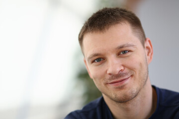 Obraz premium Smiling cheerful guy in black t-shirt staying in room while posing at camera. Lifestyle concept