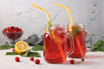 Lemonade or cocktail with raspberries, mint, lemon and ice on a grey concrete table, horizontal format, close-up
