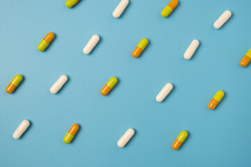 Close up of many different pills arranged in pattern on blue background.