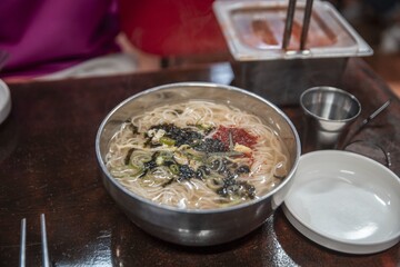 Closeup shot of a bowl with tasty Korean noodle soup at a restaurant
