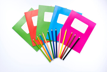 Colorful school exercise books and drawing pencils on white background.