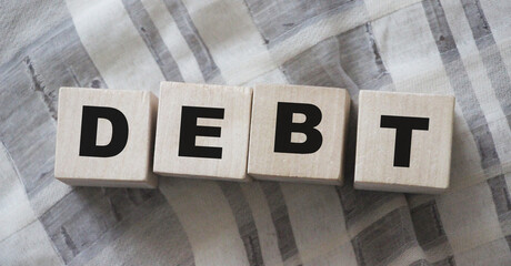 DEBT word on wooden blocks. Unprofitable business or personal loss concept - obrazy, fototapety, plakaty