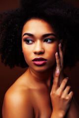 pretty young african american woman with curly hair posing cheerful gesturing on brown background, lifestyle people concept