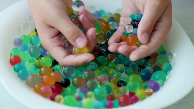 Children is hands play orbeez in a plate. Decoration with water balls hydrogel - orbeez.