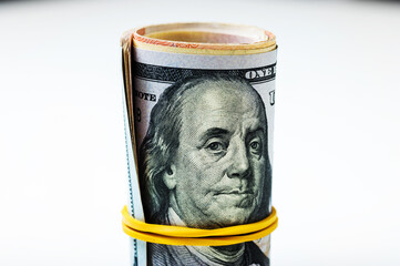 US dollars are rolled up and tightened with a rubber band, isolated on a white background, with a face value of 100.