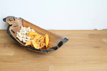 Dried fruit and nuts. Lovely wooden plate with  raw cashew nut and dried mango slices on a wooden...