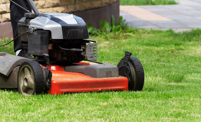 Lawn mower on the green grass. The gardener mows the lawn.