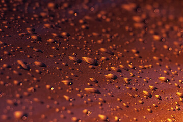 Drops of water on a red metal surface.