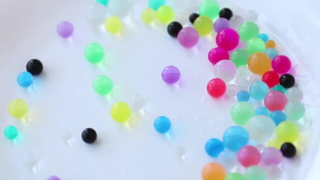 Orbiz rotate and pours on a white background. Decoration of water balls with hydrogel - orbeez.
