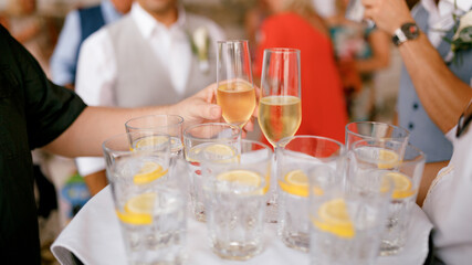 The waiter hands out champagne glasses and glasses of lemon water.