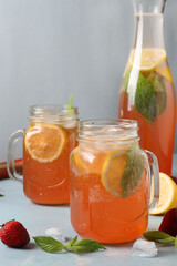 Fototapeta na wymiar Lemonade or cocktail rhubarb, strawberry, mint, lemon and ice on a light blue concrete table, vertical format, close-up