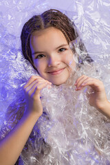 Fashion model girl posing in studio through transparent film
