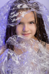 Fashion model girl posing in studio through transparent film
