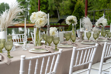 Decorated wedding table, white peonies and feathers. Chiavari chairs are at the table.