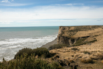 Fototapeta na wymiar Seascape. The cape from the top of the cliffs. View of the turquoise ocean water, waves, horizon and beach in a summer sunny day. 