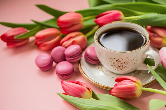 Cup of coffee with tulips on a pink background, romantic photo