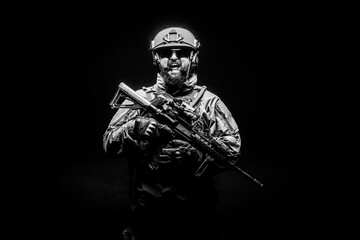 angry soldier in uniform with a rifle screaming at night, commando in stress on a black background, portrait of a ranger