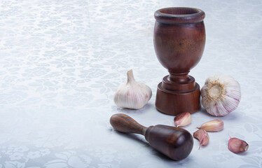 wooden mortar and garlic on a white towel.
