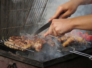 Man fries meat on the grill, hands closeup