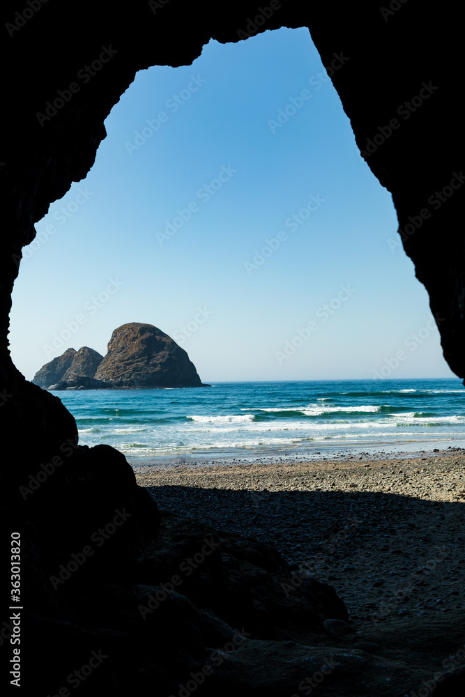 Wall mural vertical image - cave exit frames view of sea stacks on beach in oregon