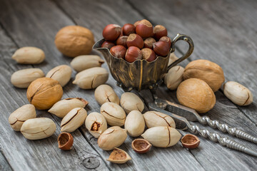 Different nuts - walnuts, hazelnuts, pecans on a wooden background with a nut cracker