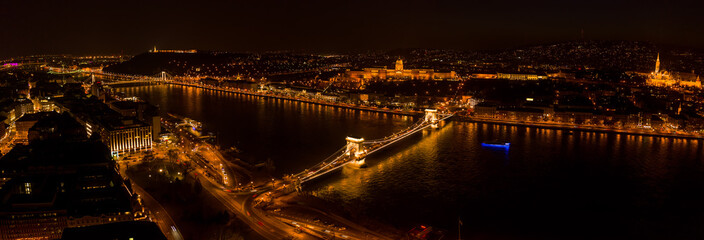 Panoramic aerial drone shot of Chain bridge over Danube and National Gallery with lights in Budapest night