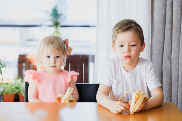 Obraz na płótnie Canvas A girl and a boy eating a banana.