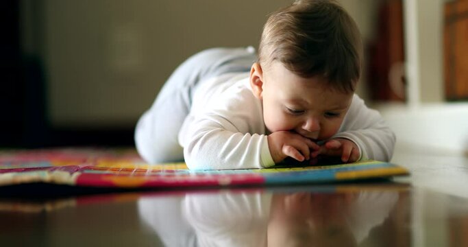 Baby learning to crawl in living-room floor. Cute toddler infant cild grabbing object