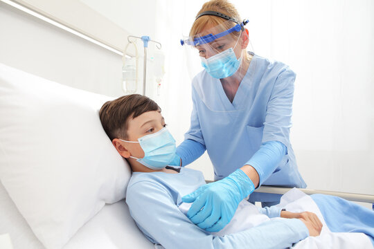 Nurse Takes Care Of The Patient Child In Hospital Bed, Wearing Protective Masks, Corona Virus Covid 19 Protection Concept,