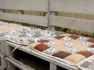 Soft pillows with floral print on a white wooden bench in the loft style on the street, close-up