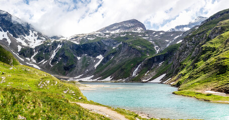 Fototapeta na wymiar clear blue lake with painty green grass in the austrian alps in the Grossglockner area 