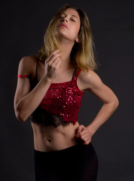 Woman in Red Sequin Top and Black Tights Against Black Background