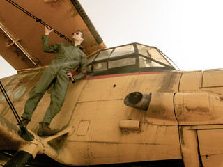 A handsome young pilot standing on the wing of a plane