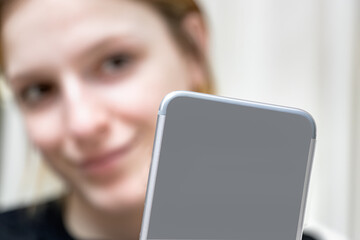 Blurred girl taking a selfie photo with her smartphone at home. Close up of the back of a mobile phone