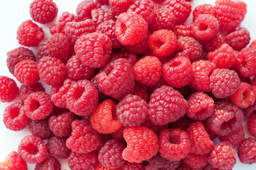 Ripe red raspberries on a white background. Sweet raspberry background. Berries close-up. Healthy food