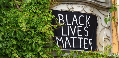Transparent an einer Fassade mit Efeu: BLACK LIVES MATER
