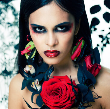 pretty brunette woman with rose jewelry, black and red, bright make up a vampire closeup red lips