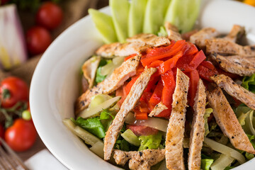 Healthy mixed salad in white bowl on wooden table.