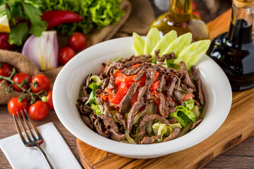 Healthy mixed salad in white bowl on wooden table.