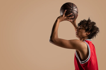 Basketball player throws the ball on brown background.