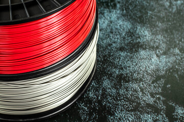Two coils of filament for 3d printing. Bright thermoplastic of red and silver colors.