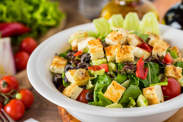 Healthy mixed salad in white bowl on wooden table.