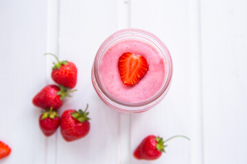 A glass of fresh strawberry smoothie on a white wooden background. Summer drink shake, Vegetarian diete and refreshment organic concept.