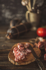 Slices of salami with tomatoes on a cutting board on a wooden table. Selective focus..