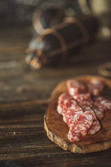 Slices of salami with tomatoes on a cutting board on a wooden table. Selective focus..